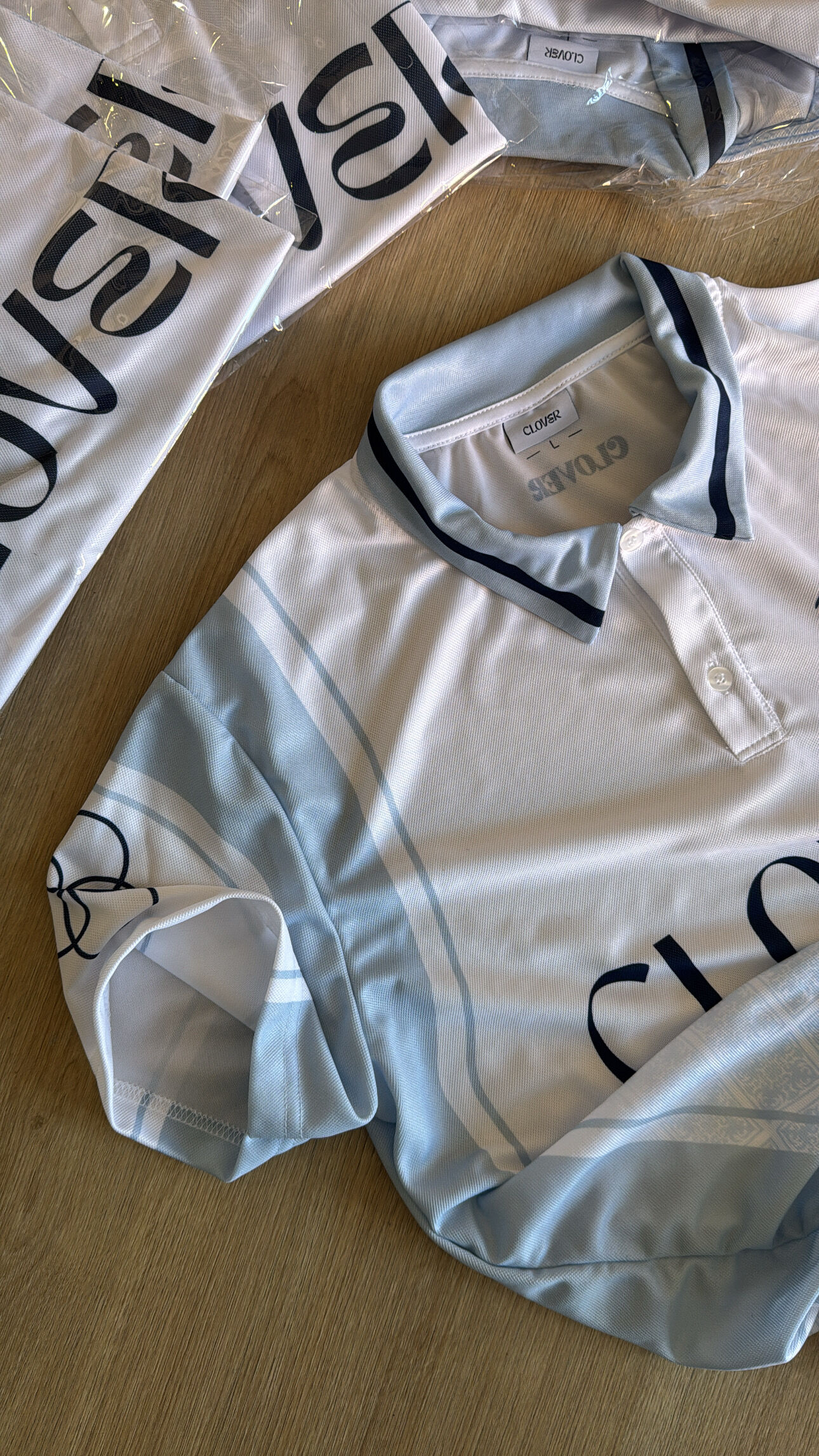Light blue Clover sublimation polo shirts on wooden surface