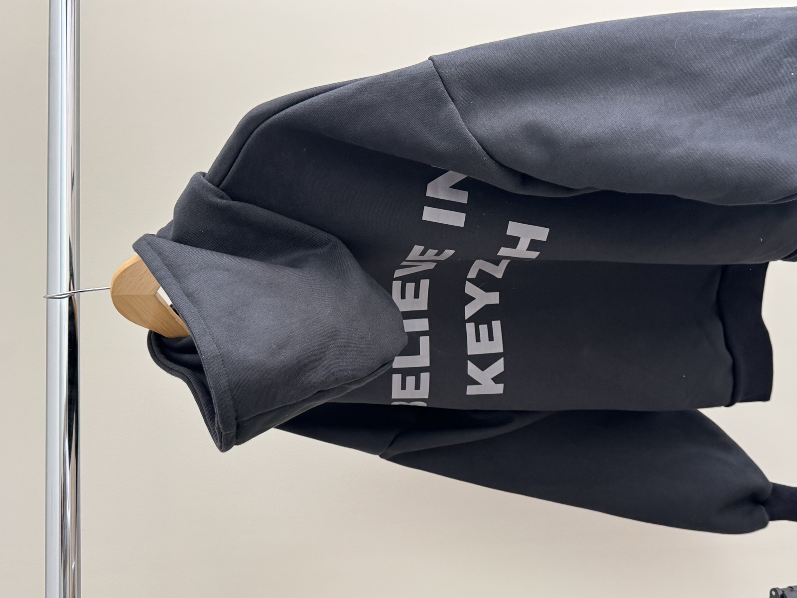 Full view of black tapered track pants with elastic waistband and small white embroidered logo laid flat