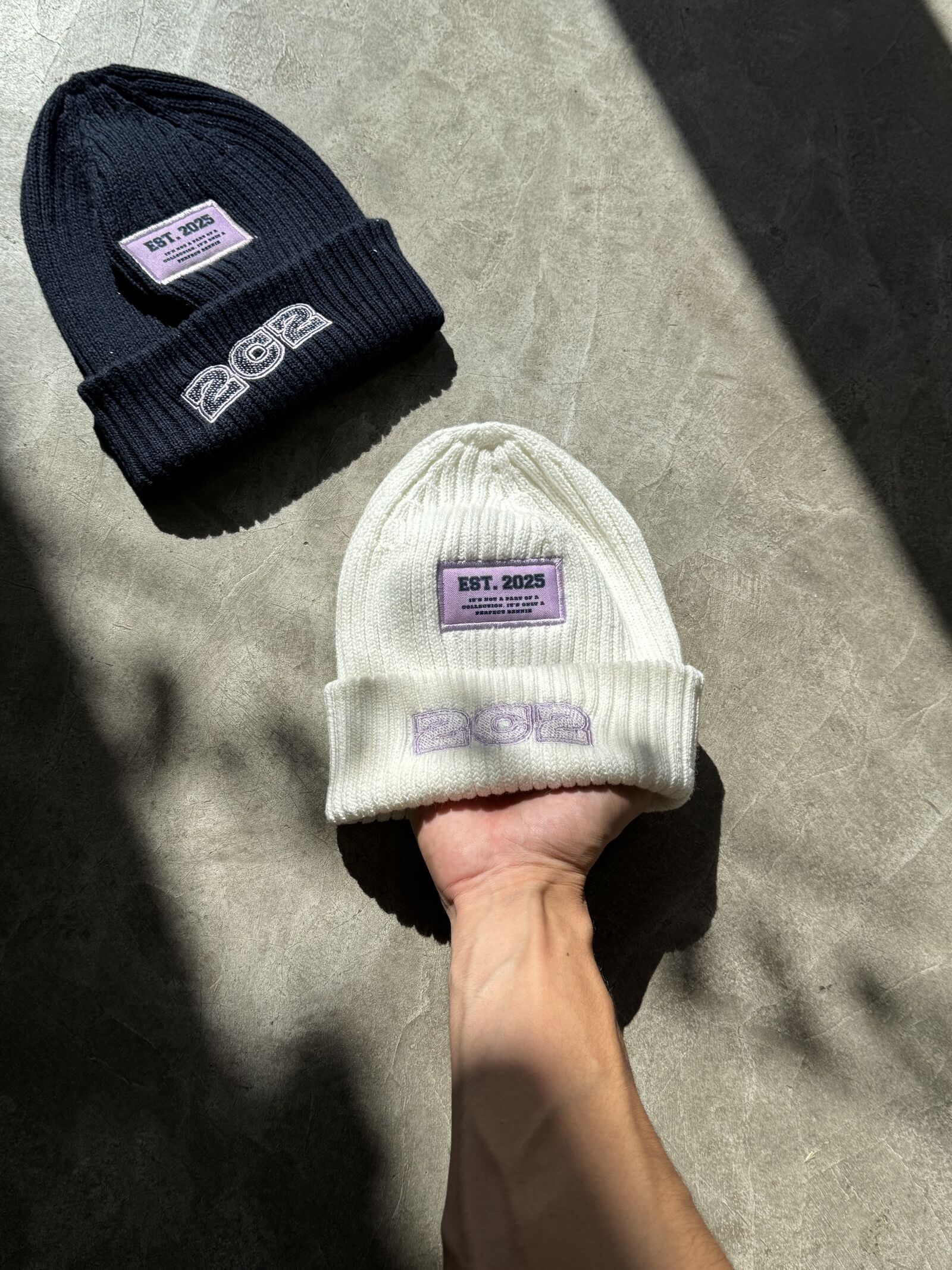 Cream and navy ribbed-knit beanies with embroidered branding