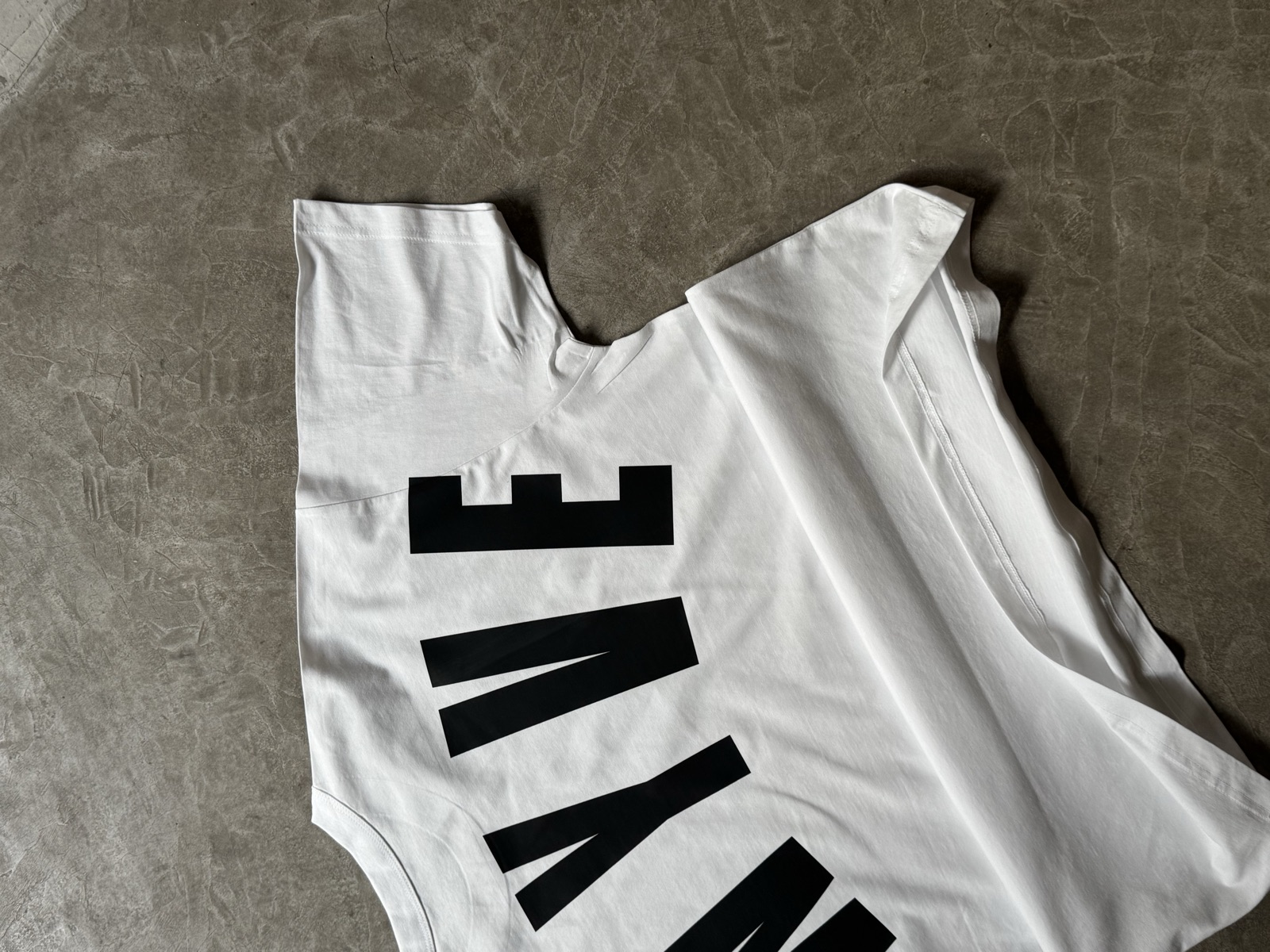 White oversized t-shirt laid flat showing large bold black typographic print across the front