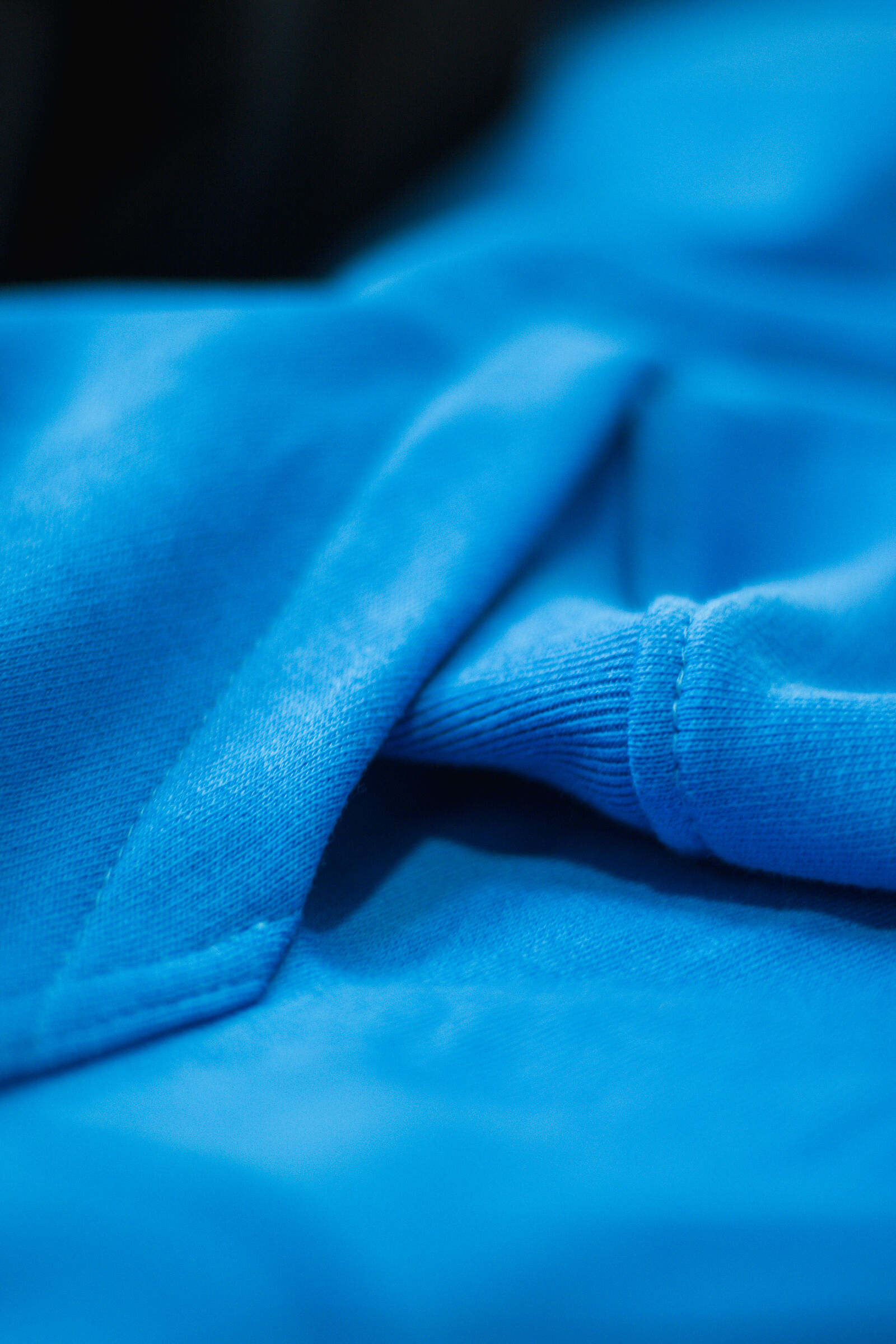 Macro close-up of royal blue cotton jersey fabric with ribbed cuff detail