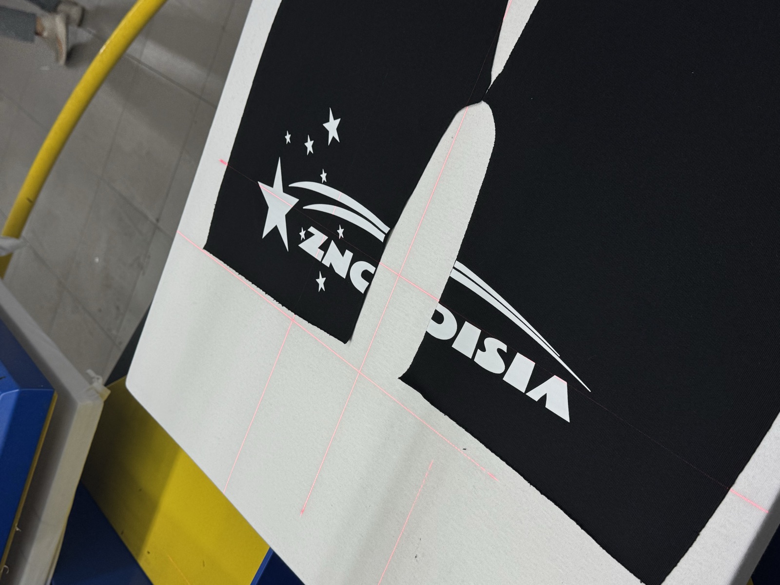 Screen printing setup showing black-and-white graphic with stars aligned under laser crosshairs on printing press