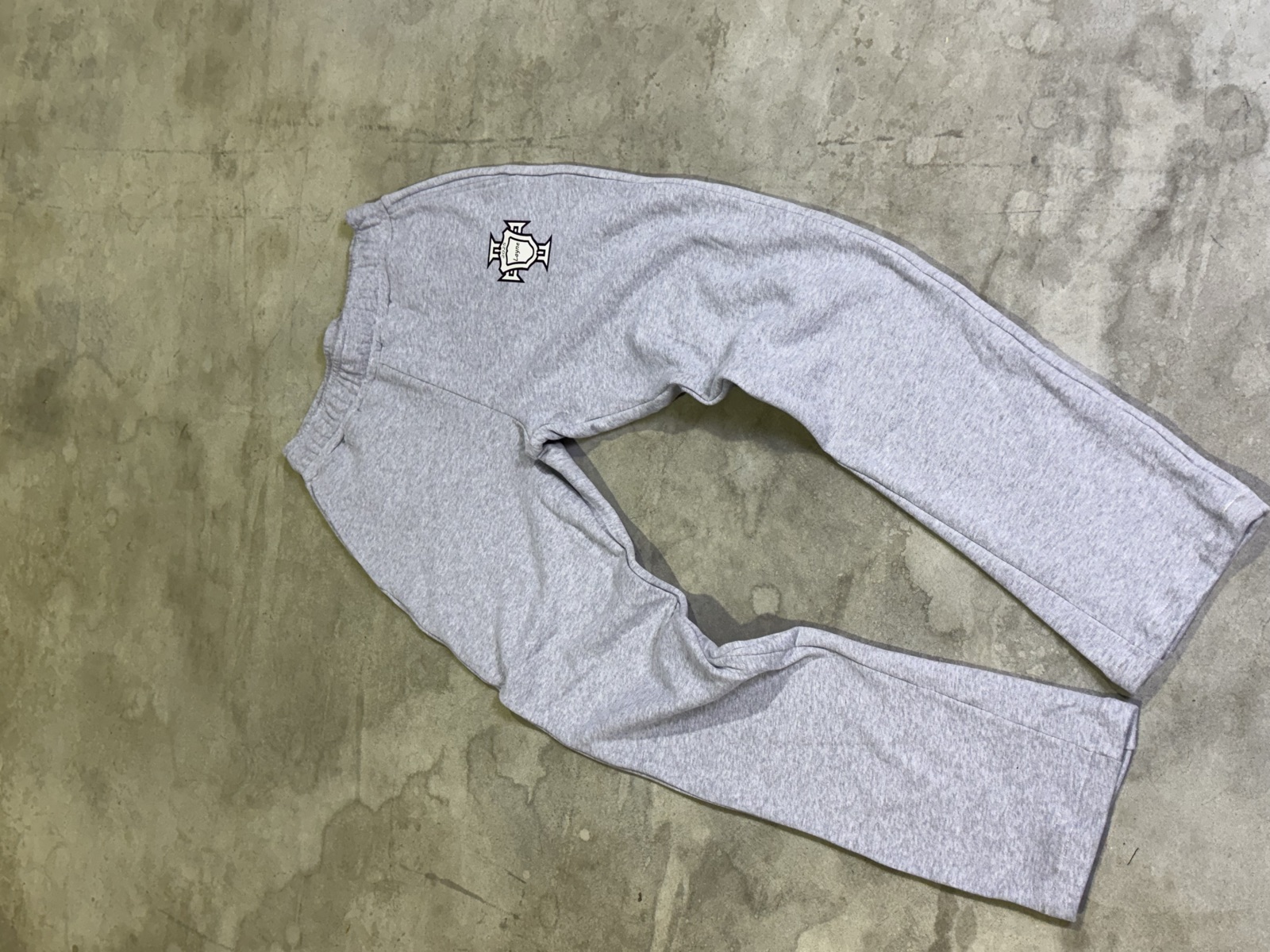 Grey heather fleece sweatpants with embroidered crest logo on upper thigh and relaxed straight-leg fit
