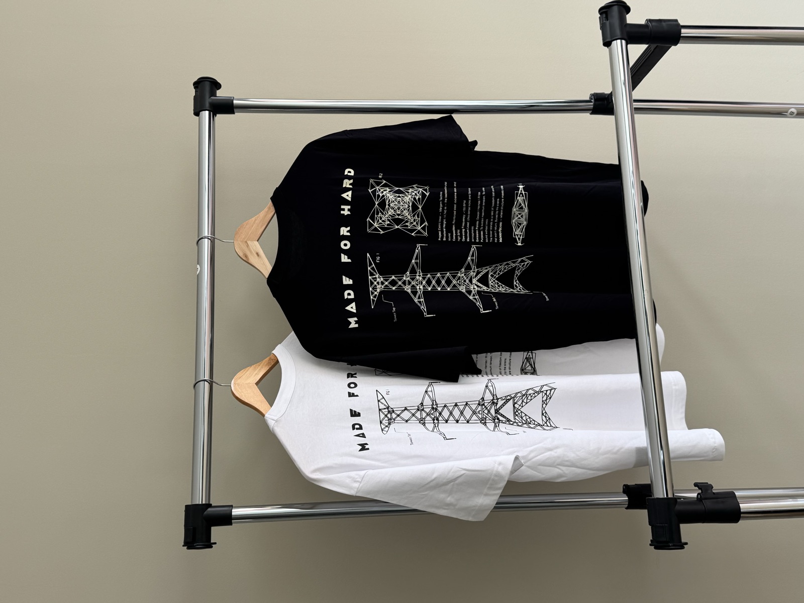 Black and white t-shirts on wooden hangers featuring geometric fish illustrations and Made for Hard text