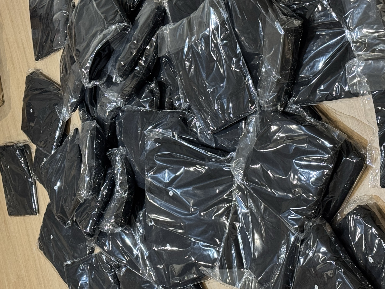 Batch of dark garments individually wrapped in clear plastic bags ready for shipping