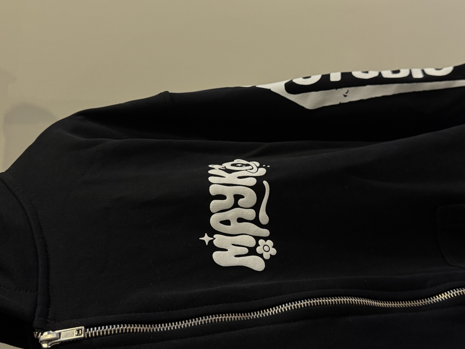 Black zip-up hoodie with white puff-print Mayko logo in playful bubble font with Studio text on hood