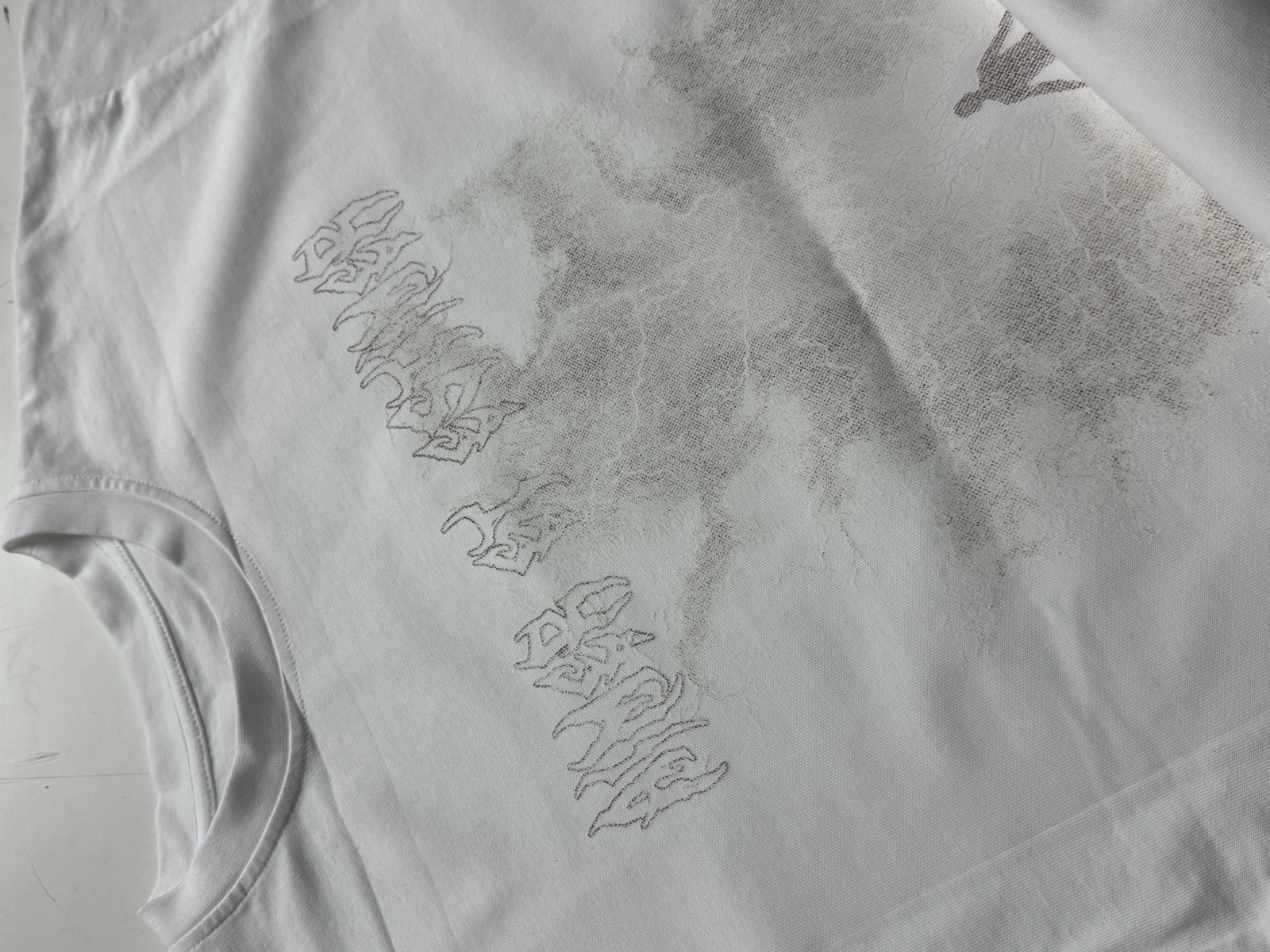 White oversized t-shirt with subtle tonal grey graphic print featuring abstract smoke effect and graffiti text