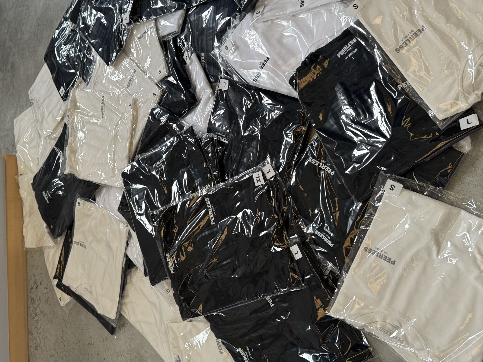 Finished garments individually packaged in clear polybags with size labels in black and white colorways