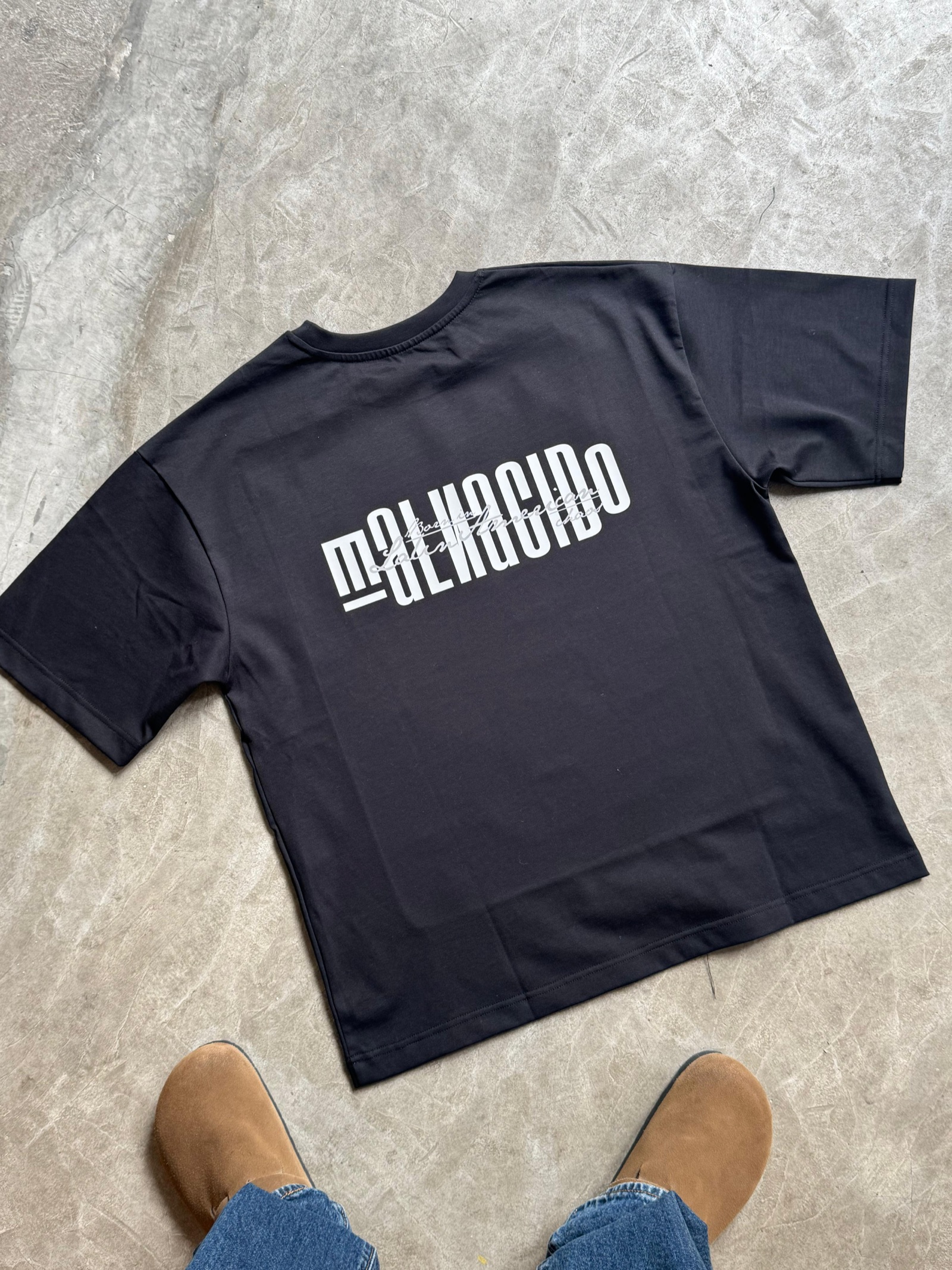 Black oversized t-shirt with bold white Malnacido crossed typography print on the back