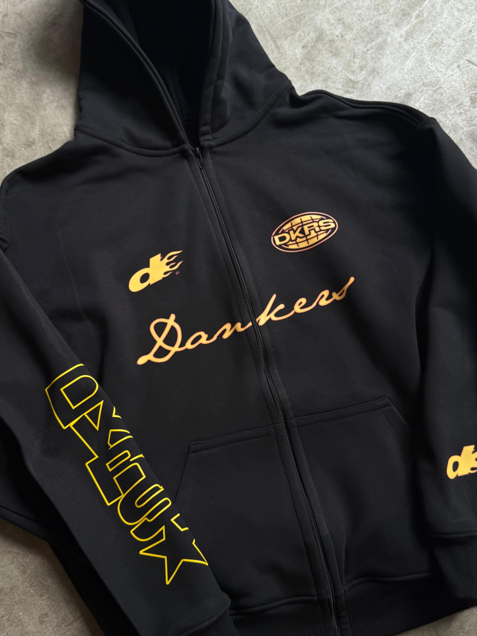 Black zip-up hoodie with yellow Dankers script embroidery and DKRS oval logo patches