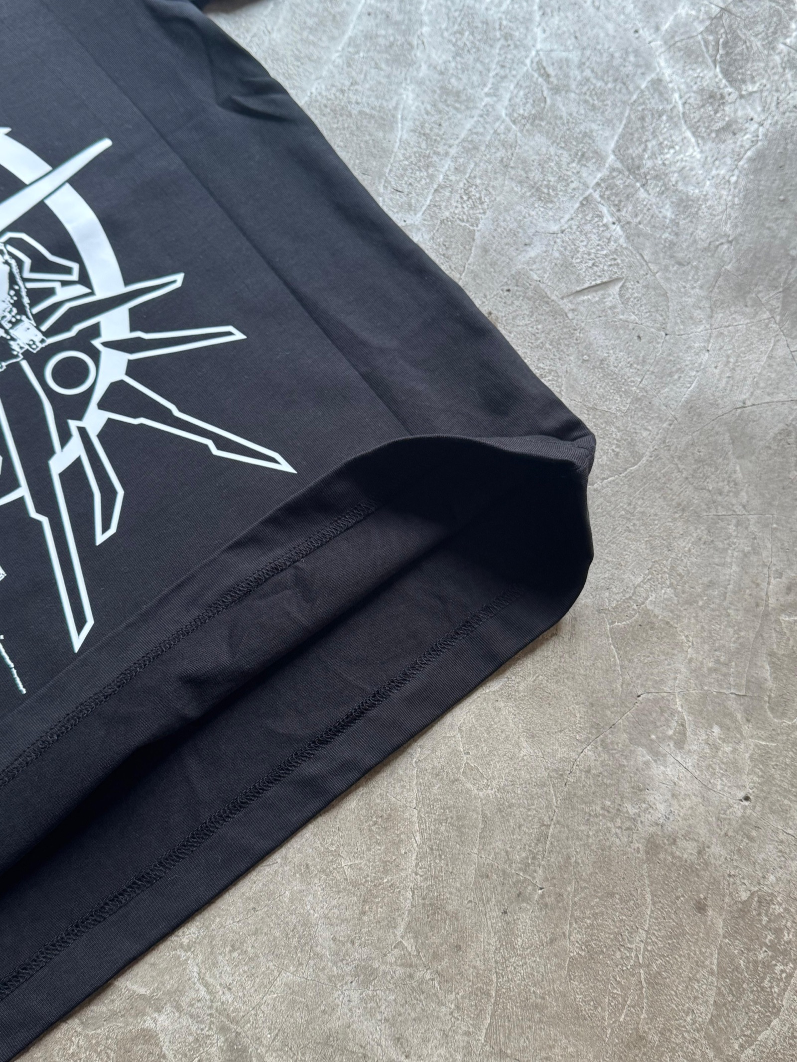 Close-up of black t-shirt sleeve and hem showing white geometric compass line art print detail