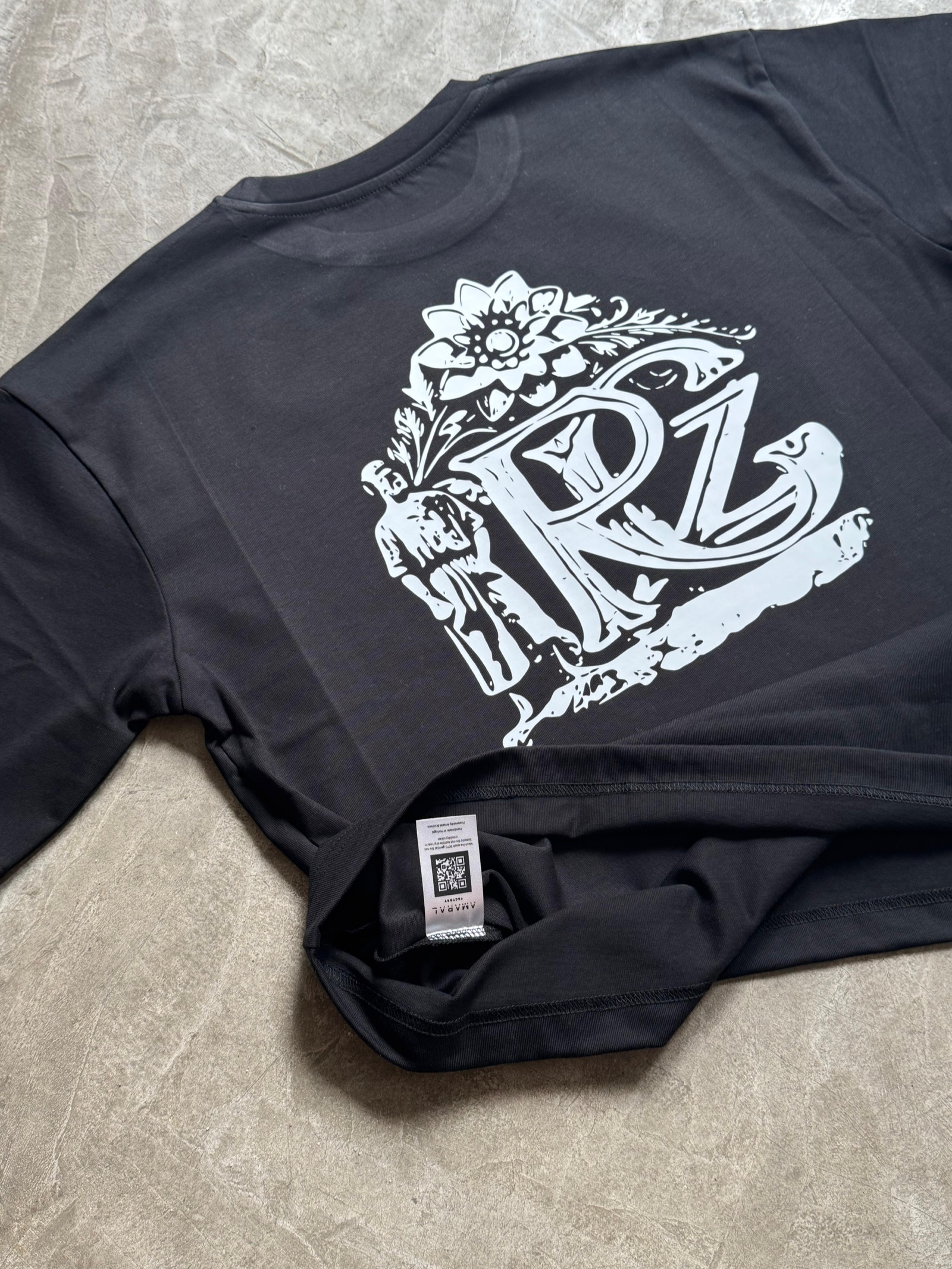 Black t-shirt with large white ornamental RL monogram crest print and QR code care label visible